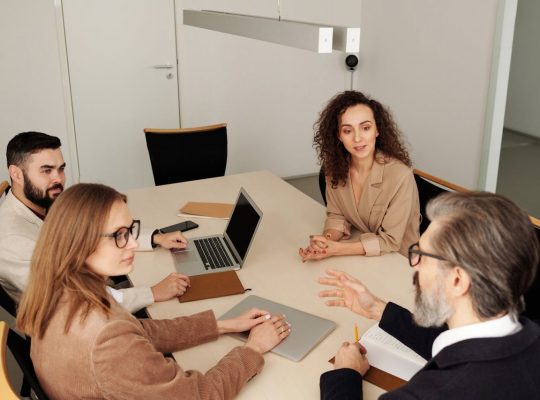 Professional team engaged in a meeting at a modern office table, discussing business strategies.